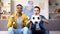 Teenage soccer fans with ball and horn cheering for football team at home