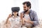 Teenage son uses virtual reality glasses next to father.