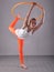 Teenage sportive girl is doing exercises with hula hoop t on grey background. Having fun playing game . Sport healthy lifestyle co