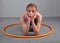 Teenage sportive girl is doing exercises with hula hoop to develop muscle on grey background. Having fun playing game . Sport heal