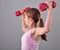 Teenage sportive girl is doing exercises to develop muscles on grey background. Sport healthy lifestyle concept. Sporty