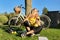 Teenage student in headphones with smartphone bicycle sitting in park