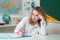 Teenage student. Portrait of a pensive young girl making notes while sitting with books.