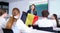 Teenage students sitting in class and listening carefully to female teacher holding Belgian flag