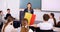 Teenage students sitting in class and listening carefully to female teacher holding Belgian flag