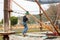 Teenage teen girl in climbing harness equipment, green sports safety helmet. Rope amusement park. Fastening