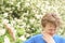 Teenager with allergies standing in a blue t-shirt among the Jasmine bushes and suffers from bad health