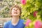 Teenager with allergies standing in a blue t-shirt among the Jasmine bushes and suffers from bad health