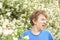 Teenager with allergies standing in a blue t-shirt among the Jasmine bushes and suffers from bad health