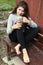 Teenager bare footed girl with cup of tea sit on bench