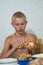 Teenager with bare torso peels potatoes