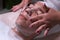 Teenager in beauty clinic. Close-up of the hands of a beautician who lathers the face of a boy. Male client gets facial