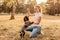 Teenager blonde girl with big glasses laughing and playing with little puppy spaniel in the warm park