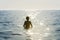 Teenager boy bathing in the sea surrounded by sunbeam reflection