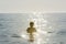 Teenager boy bathing in the sea surrounded by sunbeam reflection