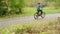 Teenager boy bicyclist riding on bicycle on path in green summer park. Young boy cycling on bicycle in city park. Sport