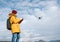 Teenager boy dressed yellow jacket piloting a modern digital drone using remote controller