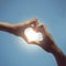 Teenager boy and girl hands in heart form love in blue sky