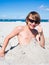 Teenager boy has fun digging in the sand at Baltic Sea