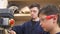 Teenager boy with his dad drills the wooden plank using industrial joinery machine in workshop