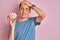 Teenager boy holding a bunch of delicious fluffy marshmallow over isolated pink background stressed with hand on head, shocked