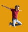 Teenager boy jumping dance movement on a colored yellow background
