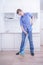 Teenager Boy Mopping The Floor and helps his parents to clean on kitchen