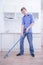 Teenager Boy Mopping The Floor and helps his parents to clean on kitchen