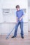 Teenager Boy Mopping The Floor and helps his parents to clean on kitchen