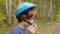 Teenager boy putting bicycle helmet on head in autumn park. Handsome boy wearing blue protective helmet for