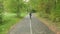 Teenager boy riding on longboard at pathway in summer park. Young boy skateboarding on skateboard in autumn park