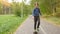 Teenager boy riding on skateboard at park pathway. Young boy riding on bicycle in autumn park. Skateboarding and cycling