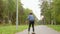 Teenager boy skateboarding on skateboard in summer city park track shot. Rear view boy teenager riding skateboard on