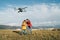 Teenager boy son dressed yellow jacket and Father piloting a modern digital drone using remote controller. Modern technology