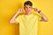 Teenager boy wearing yellow t-shirt over isolated background covering ears with fingers with annoyed expression for the noise of