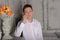 Teenager boy in a white shirt and pants leaning on a marble fireplace shelf next to a vase of flowers