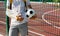 Teenager with broken arm holding football ball next to sports ground. Boy in white t shirt with hand splint in a arm sling