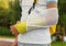 Teenager with broken arm next to the sports ground. The boy in a white t-shirt with a hand splint in an arm sling for support