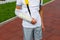 Teenager with broken arm next to the sports ground. Boy in a white t-shirt with hand splint in an arm sling for support
