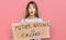 Teenager caucasian girl holding mother nature is crying protest cardboard banner scared and amazed with open mouth for surprise,