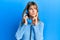 Teenager caucasian girl speaking on vintage telephone serious face thinking about question with hand on chin, thoughtful about