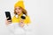 Teenager caucasian girl with yellow hat listen to music with big earphones, phone and serfing the internet isolated on