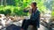 Teenager caucasian woman sitting with tired and drinking water for journey in the forest.