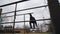 A teenager climbs on metal bars on an old sports field.