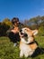 A teenager communicates with a corgi dog in a sunny autumn meadow