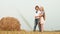 Teenager couple embracing on countryside field on haystack background. Young couple teenager girl and boy hugging on