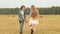 Teenager couple holding hands walking on rural field on haystack background. Romantic girl and boy turning on harvesting