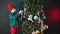 A teenager decorates a Christmas tree against a dark background.