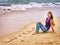 Teenager draw love on sand near waves.