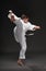 A teenager dressed in martial arts clothing poses on a dark gray background, a sports concept